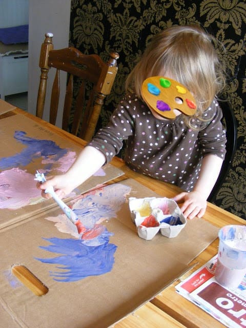 a-kid-painting-on-cardboard-box