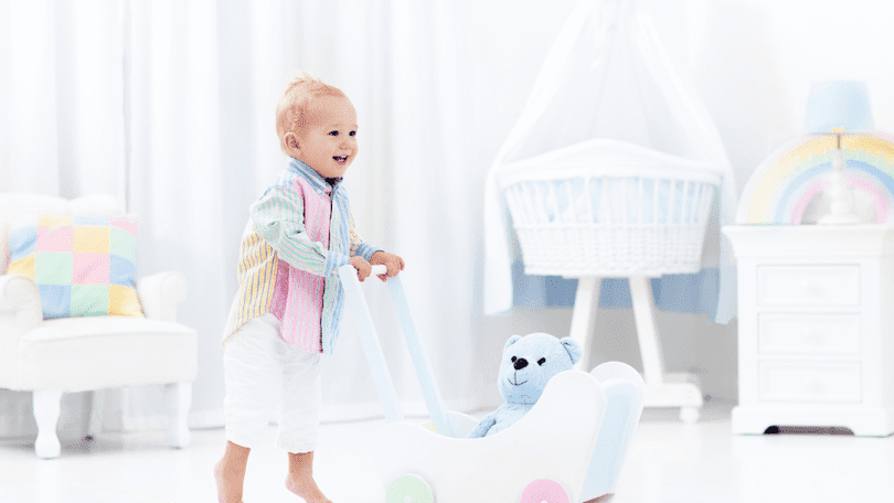 colorful-infant-using-a-wooden-push-walker-with-toys